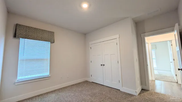 a view of an empty room with closet and a window