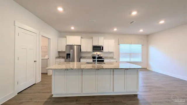 a kitchen with stainless steel appliances granite countertop a stove a sink and a refrigerator with wooden floor