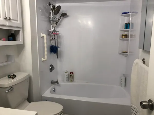 a white bath tub sitting next to a white toilet and vanity