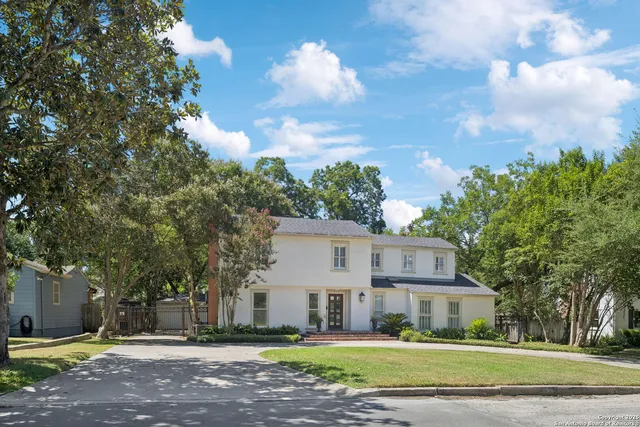 a view of a house with a big yard and large trees