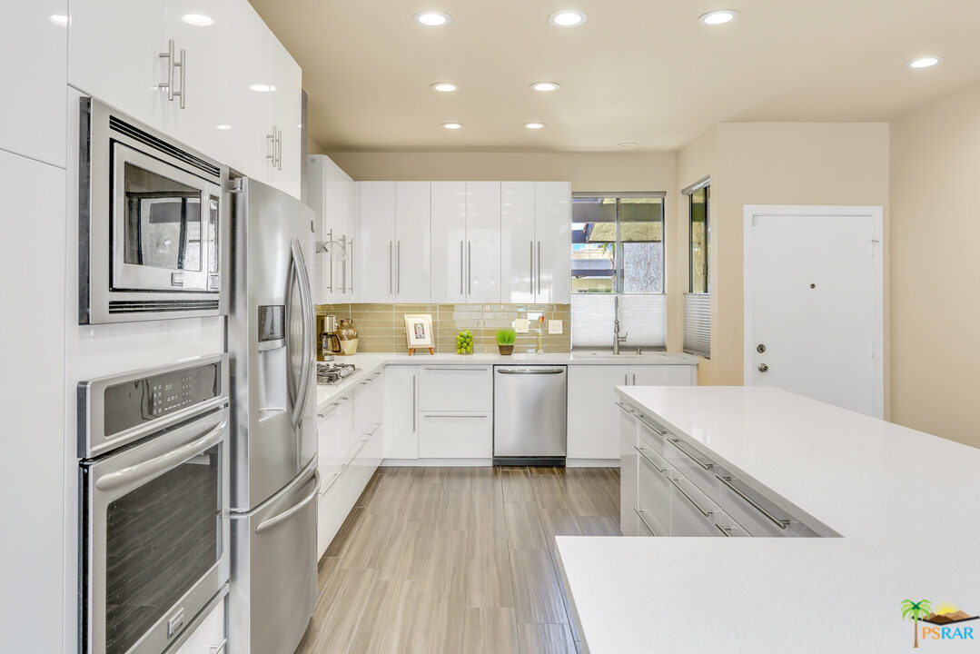 1314 East Andreas Road Palm Springs, CA 92262 - Photo 11 of 34 a kitchen with a sink dishwasher a refrigerator and white cabinets with wooden floor