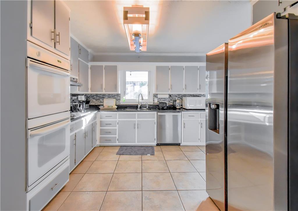 1679 Rangewood Drive Southwest Lilburn, GA 30047 - Photo 15 of 22 a kitchen with stainless steel appliances granite countertop a refrigerator a sink a stove and white cabinets