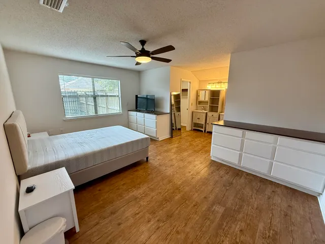 a spacious bedroom with a bed windows and wooden floor