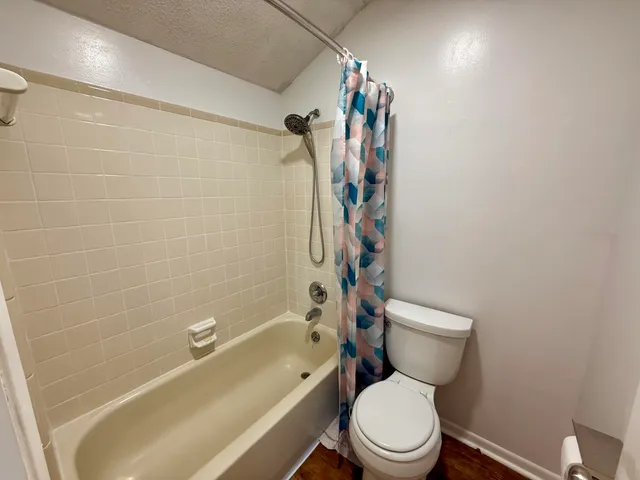 a white toilet sitting next to a bath tub and a shower