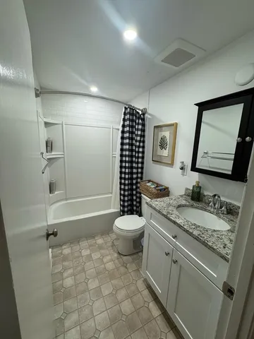 a bathroom with a granite countertop toilet a sink a mirror and shower