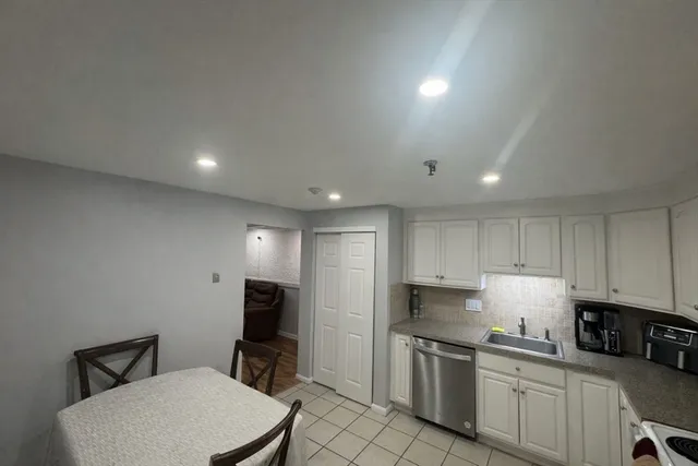 a kitchen with a sink a stove a refrigerator cabinets and a dining table