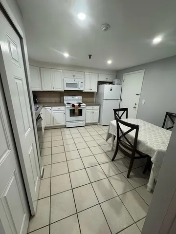 a kitchen with stainless steel appliances kitchen island granite countertop a rug a stove a microwave and a dining table with wooden floor