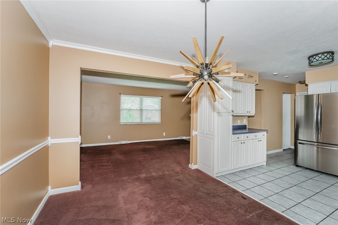 215 Randel Avenue Akron, OH 44313 - Photo 6 of 20 Kitchen with crown molding, stainless steel fridge, light tile floors, and white cabinetry