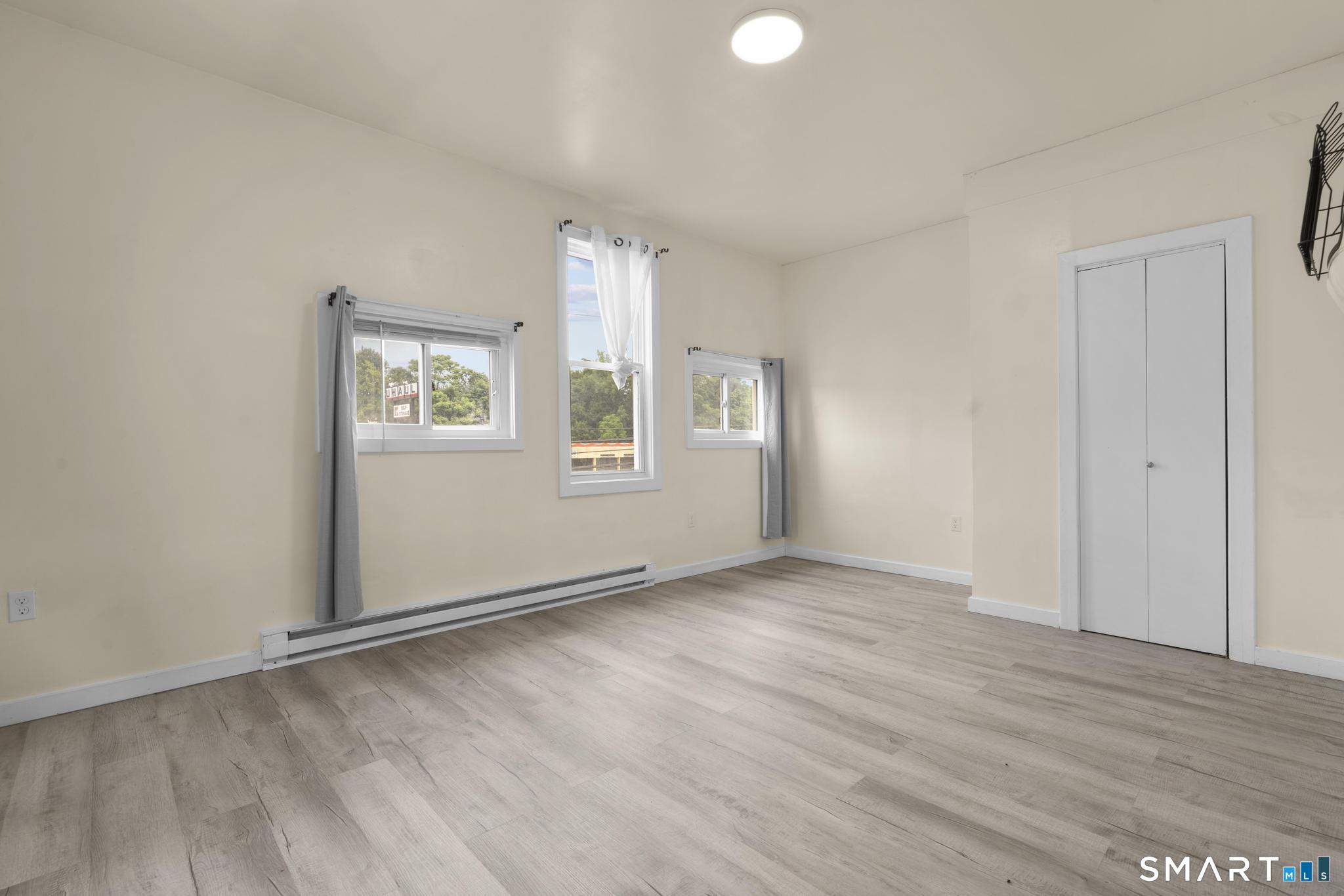170 Meriden Road Waterbury, CT 06705 - Photo 5 of 26 an empty room with wooden floor and windows