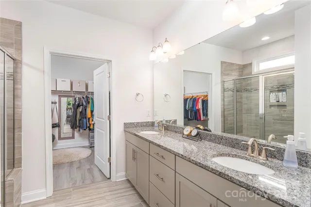 a bathroom with a granite countertop double vanity sink and a mirror