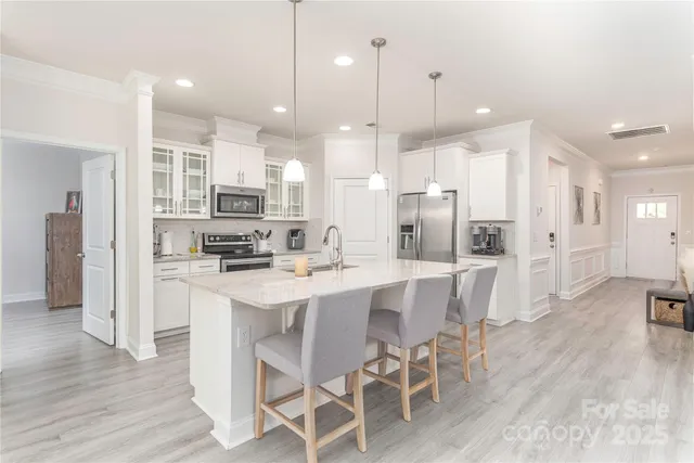 a kitchen with stainless steel appliances kitchen island granite countertop a dining table chairs and sink