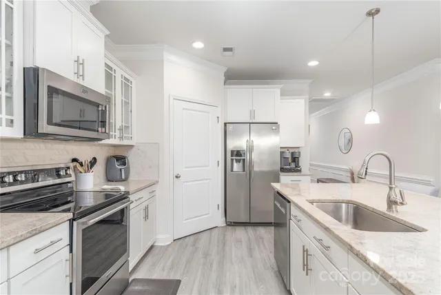 a kitchen with stainless steel appliances granite countertop a sink stove microwave and refrigerator