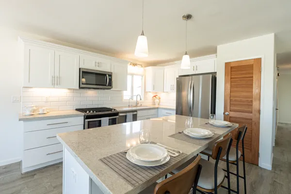 a kitchen with stainless steel appliances granite countertop a stove a refrigerator a kitchen island a dining table and chairs