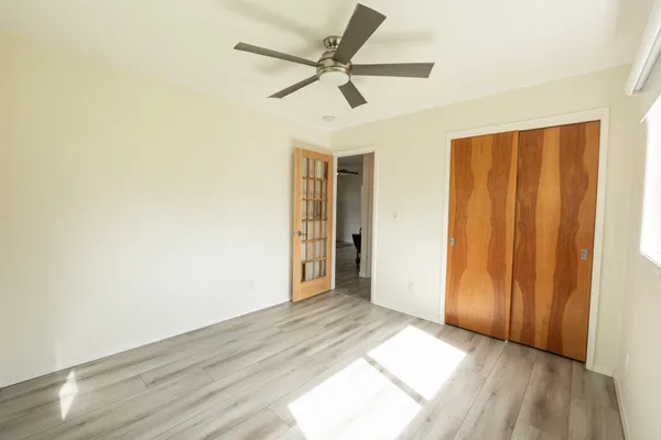 an empty room with wooden floor fan and windows