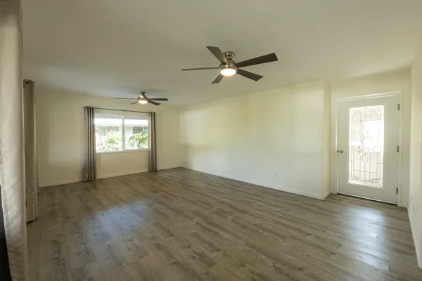 a view of empty room with wooden floor and fan