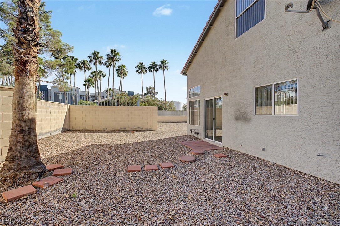2223 Ramsgate Drive Henderson, NV 89074 - Photo 23 of 32 A low-maintenance gravel yard offers a blank canvas for outdoor living, framed by a sturdy block fence and mature palm trees.