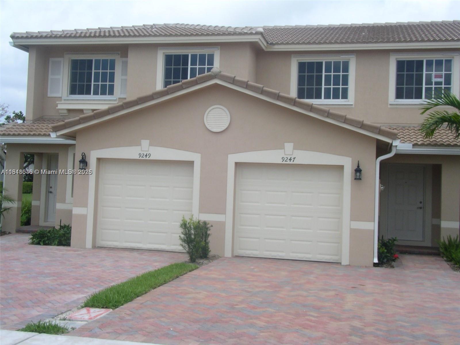 9247 Chambers Street Tamarac, FL 33321 - Photo 2 of 21 a front view of a house with a garden and garage