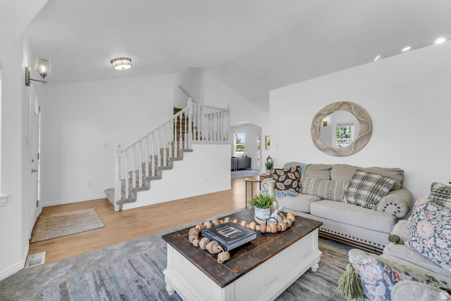 1147 West State Road Lehi, UT 84043 - Photo 3 of 31 Bright living area featuring wood-finish flooring and a carpeted staircase with white railings