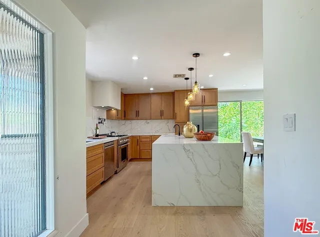 a large kitchen with kitchen island a large counter top space a sink stainless steel appliances and cabinets