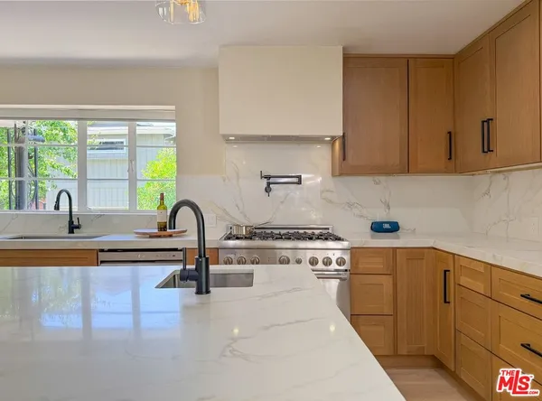 a kitchen with stainless steel appliances granite countertop a sink a stove and a wooden floors