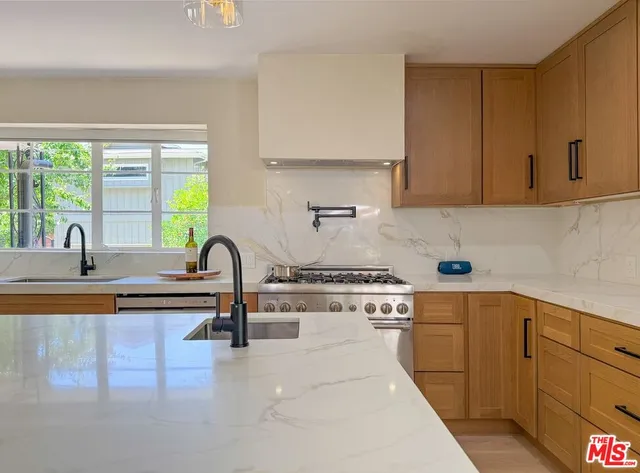 a kitchen with stainless steel appliances granite countertop a sink a stove and a wooden floors
