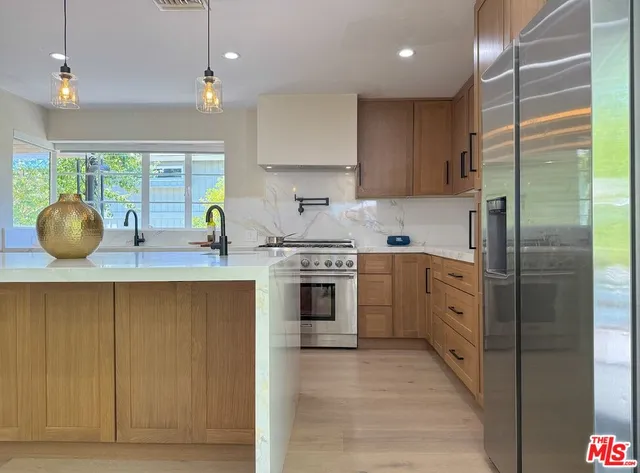 a kitchen with stainless steel appliances granite countertop a stove a sink and a refrigerator