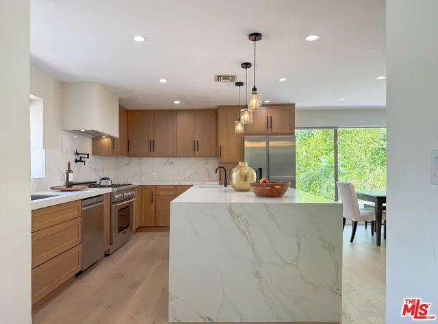 a large kitchen with kitchen island a large counter space a sink a window and stainless steel appliances