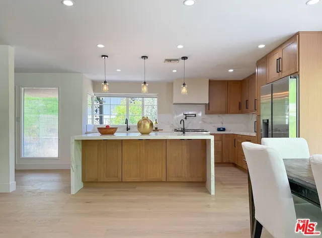 a large kitchen with kitchen island a large counter space a sink a window and stainless steel appliances