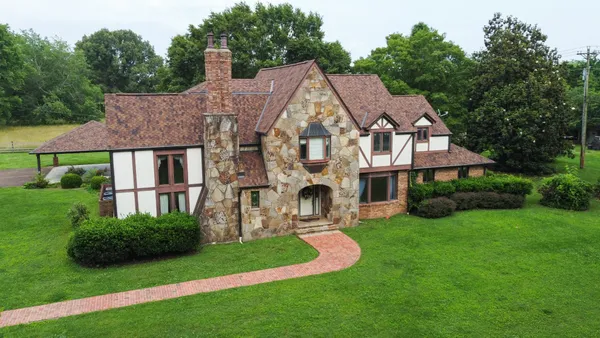 a aerial view of a house next to a big yard and large trees