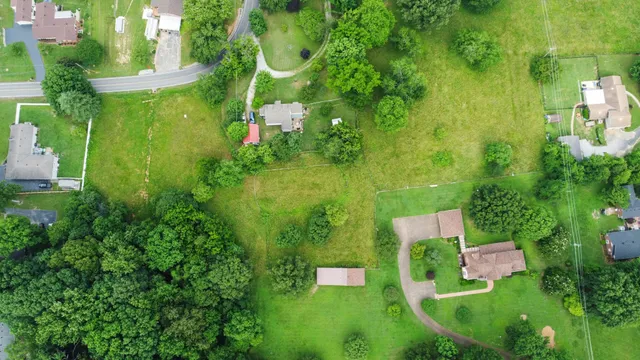 an aerial view of residential house with outdoor space and trees all around