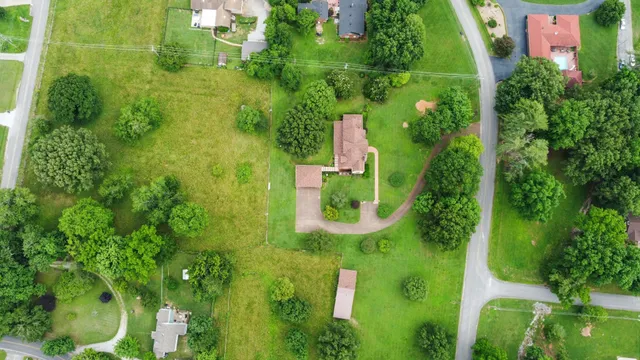 an aerial view of residential house with an outdoor space and trees all around