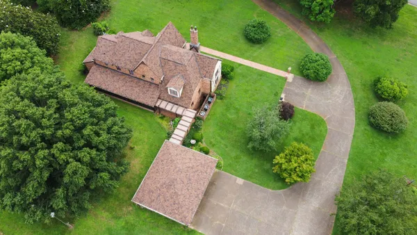 a aerial view of a house next to a big yard and large trees