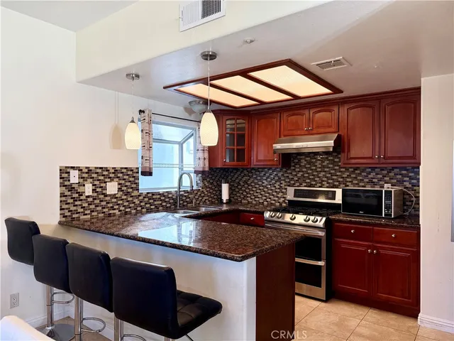 a kitchen with stainless steel appliances granite countertop a stove a sink and a microwave