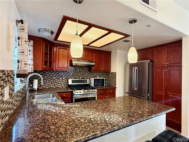 a kitchen with stainless steel appliances granite countertop a sink stove and refrigerator