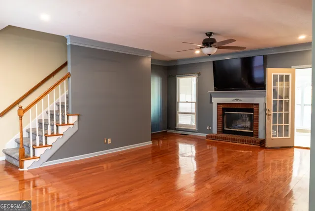 a view of an empty room with wooden floor fireplace and a window