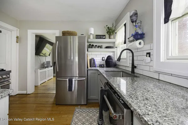a kitchen with stainless steel appliances granite countertop a refrigerator a stove and a sink with wooden floor