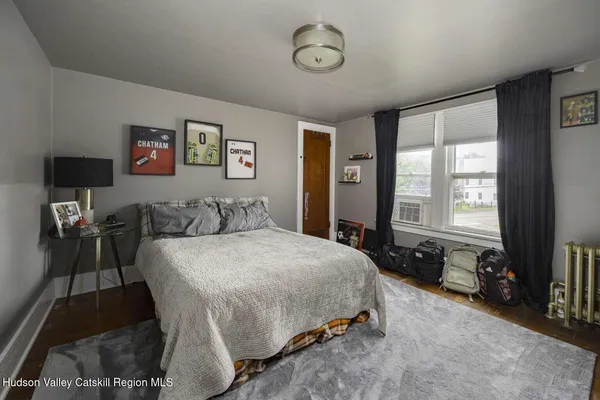 a spacious bedroom with a bed a dresser and a large window