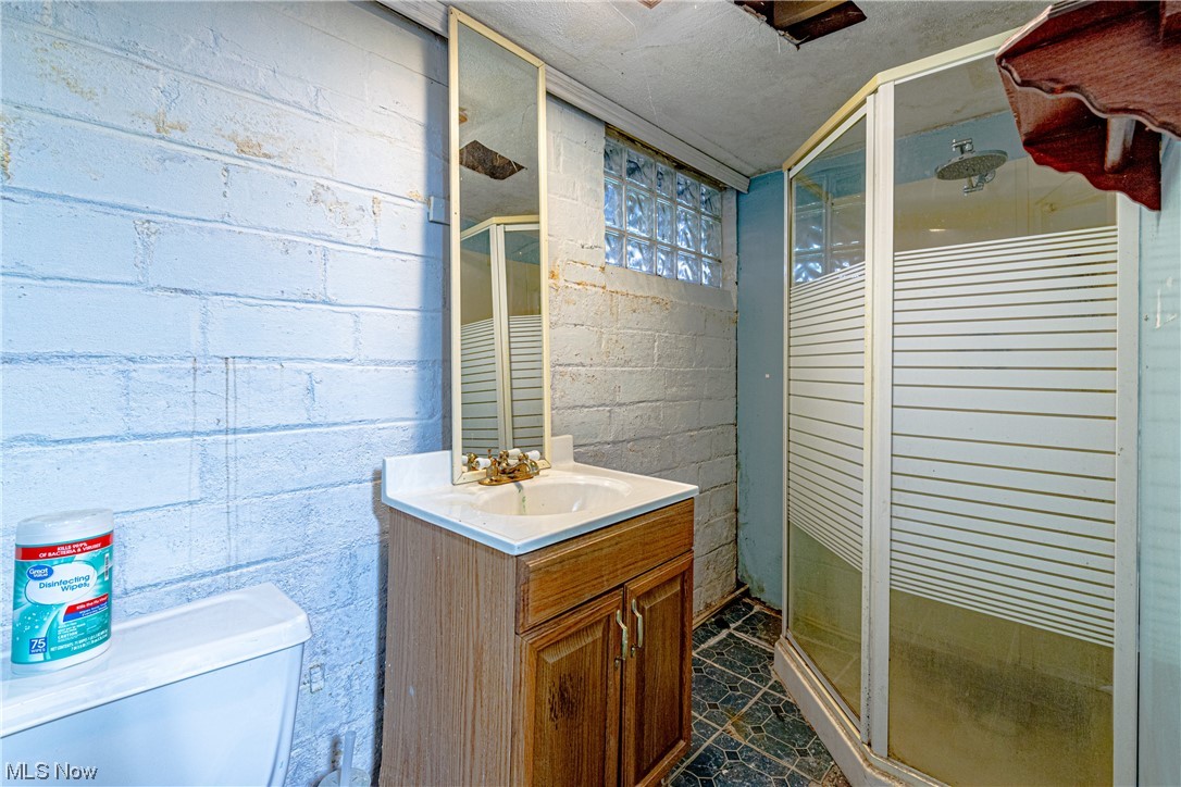 3337 Ralph Avenue Cleveland, OH 44109 - Photo 26 of 30 Bathroom with toilet, oversized vanity, tile flooring, walk in shower, and brick wall