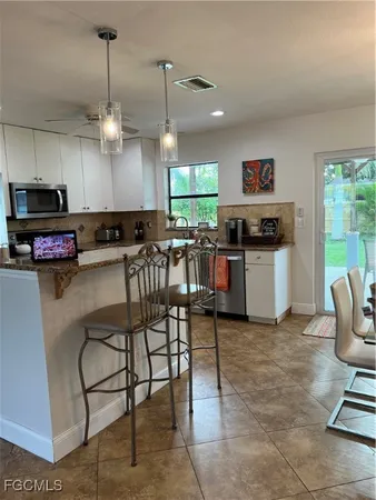 a kitchen with kitchen island granite countertop a stove a sink a dining table and chairs in it