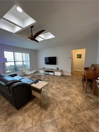 a living room with furniture a flat screen tv and a large window