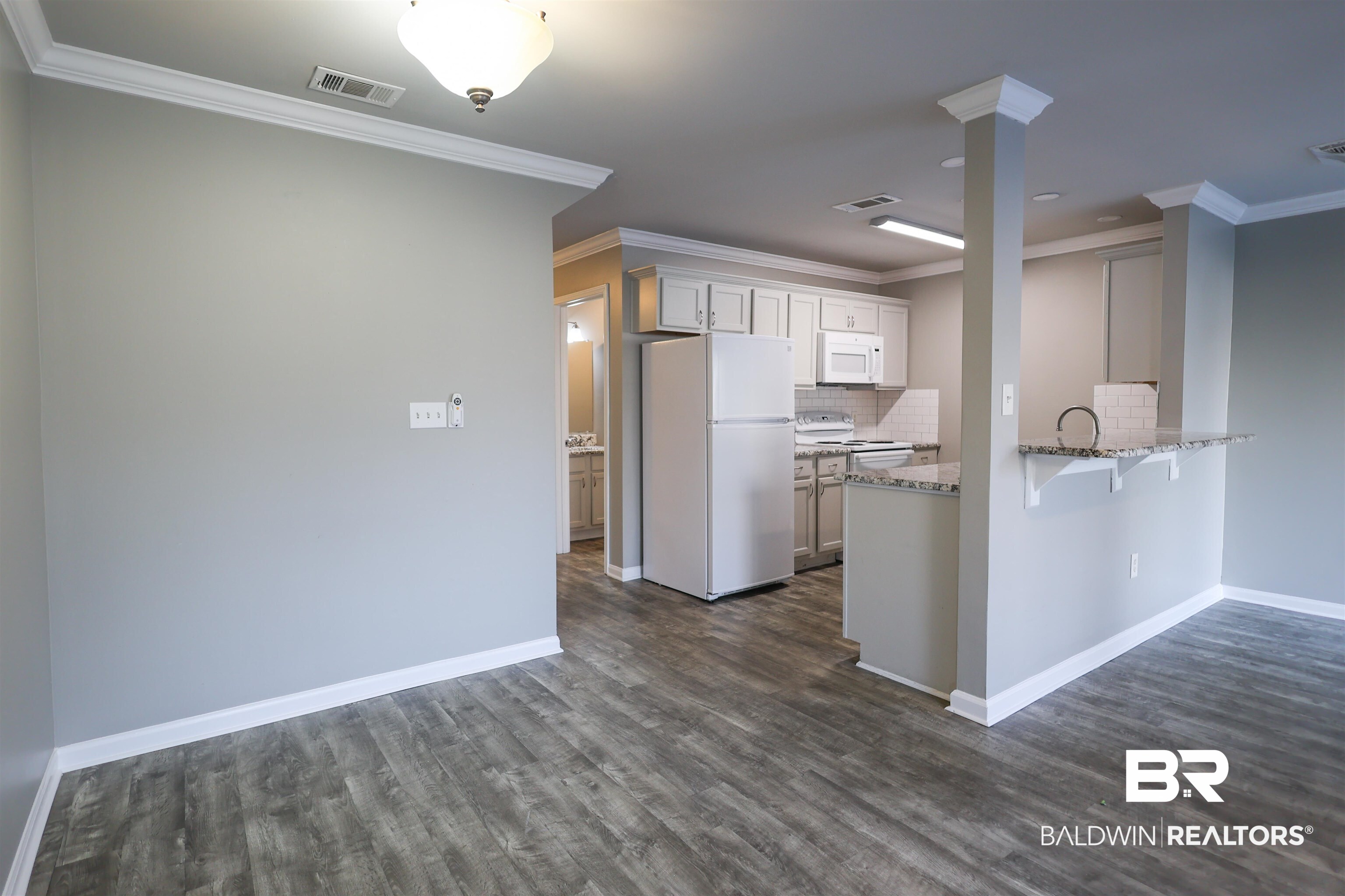 1517 Regency Road, Unit 125 Gulf Shores, AL 36542 - Photo 10 of 26 Kitchen featuring white appliances, light stone countertops, ornamental molding, a kitchen bar, and tasteful backsplash