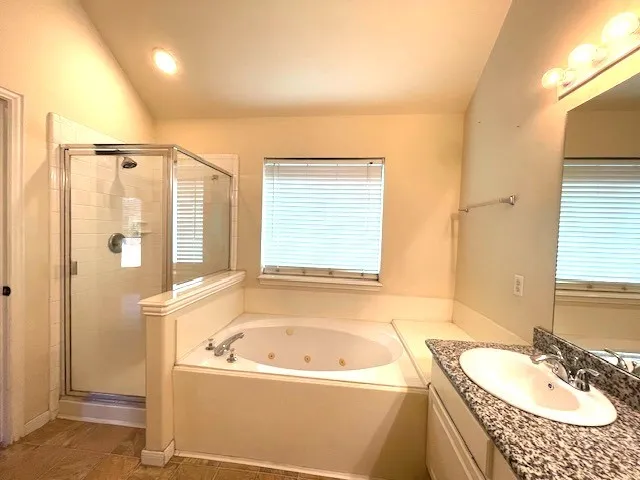 a bathroom with a granite countertop tub and a sink