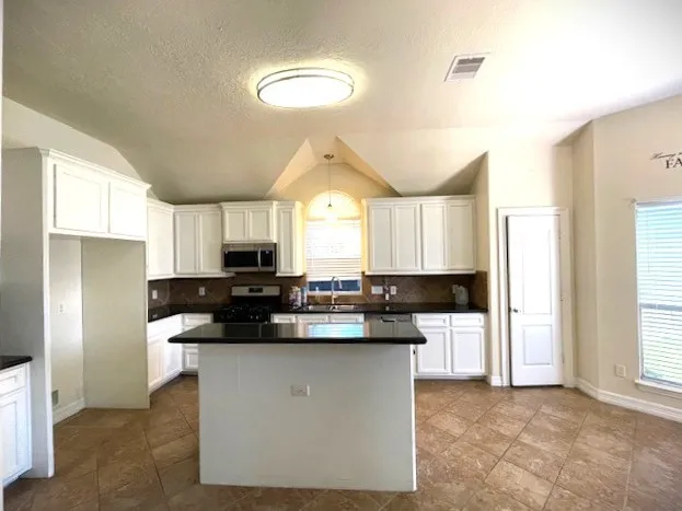 a kitchen with stainless steel appliances granite countertop a sink a stove a refrigerator a sink a counter space and cabinets