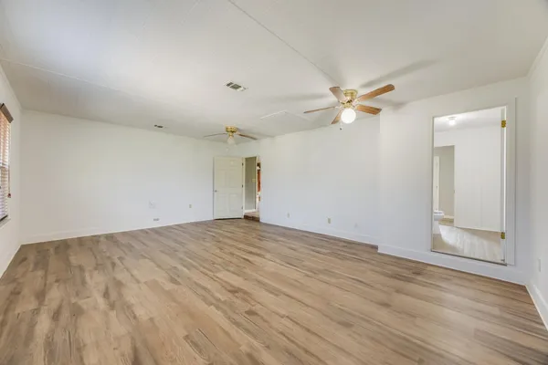 an empty room with wooden floor and ceiling fan