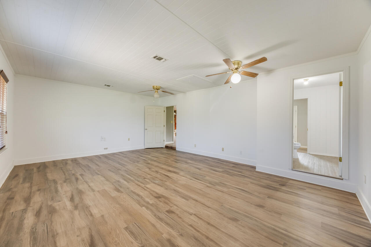 5811 Monroe Street Baker, FL 32531 - Photo 17 of 33 an empty room with wooden floor and ceiling fan