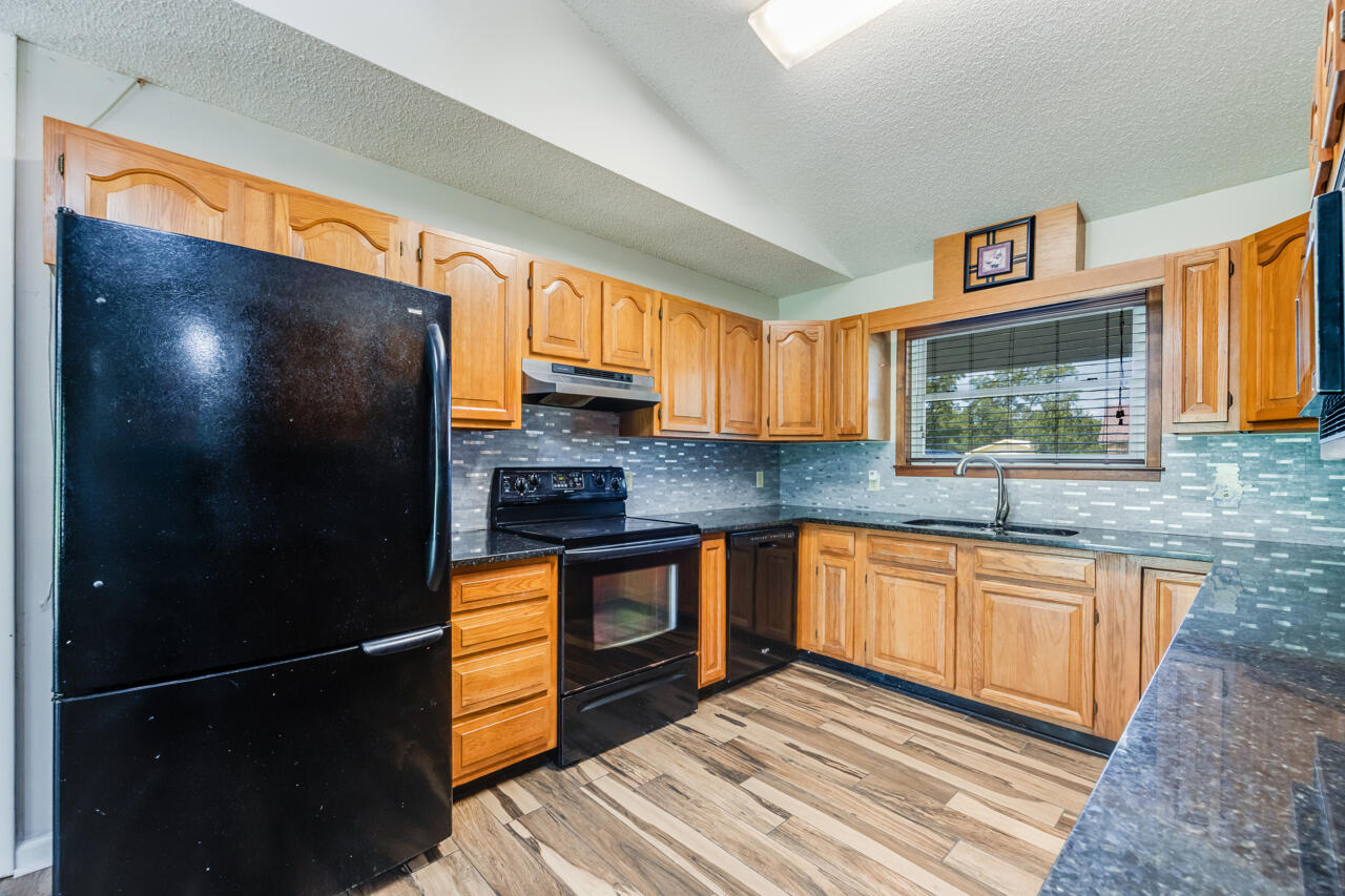 5811 Monroe Street Baker, FL 32531 - Photo 10 of 33 a kitchen with stainless steel appliances granite countertop a refrigerator a sink a stove with wooden cabinets and floor