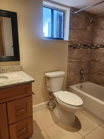 a bathroom with a granite countertop toilet sink and mirror