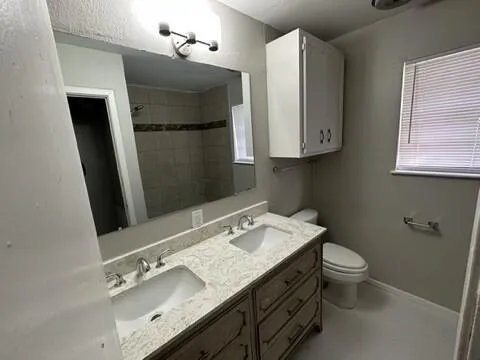 a bathroom with a granite countertop sink toilet and a mirror