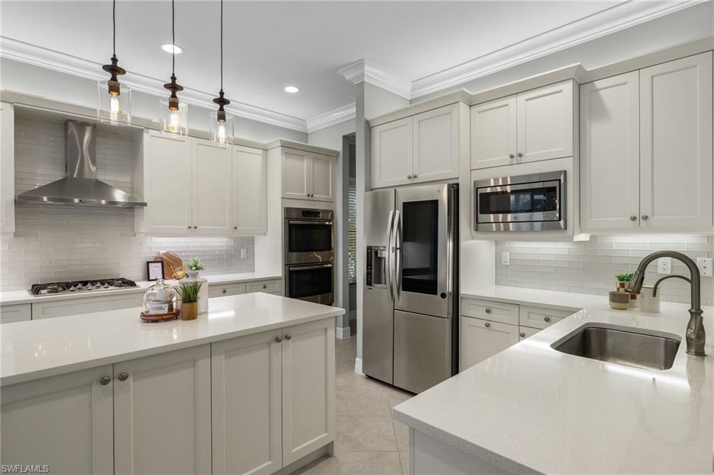 4398 Caldera Circle Naples, FL 34119 - Photo 12 of 50 a kitchen with stainless steel appliances a sink a stove a refrigerator and cabinets