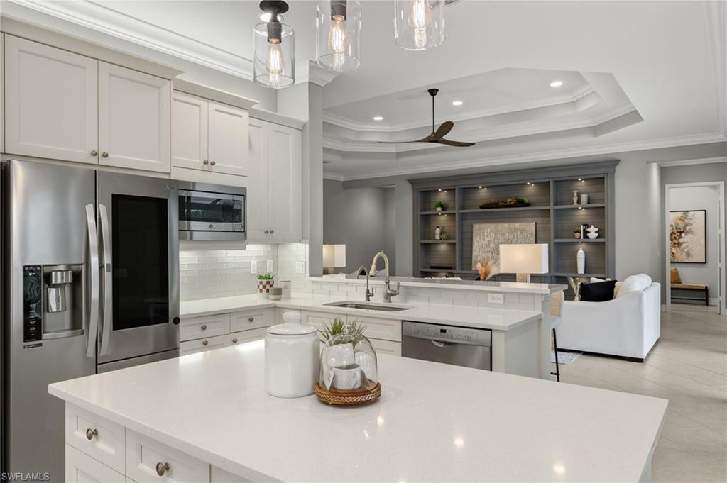 4398 Caldera Circle Naples, FL 34119 - Photo 13 of 50 a kitchen with a sink dishwasher a stove and white cabinets with wooden floor